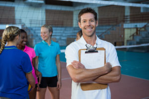 Portrait of smiling male coach standing in the volleyball court